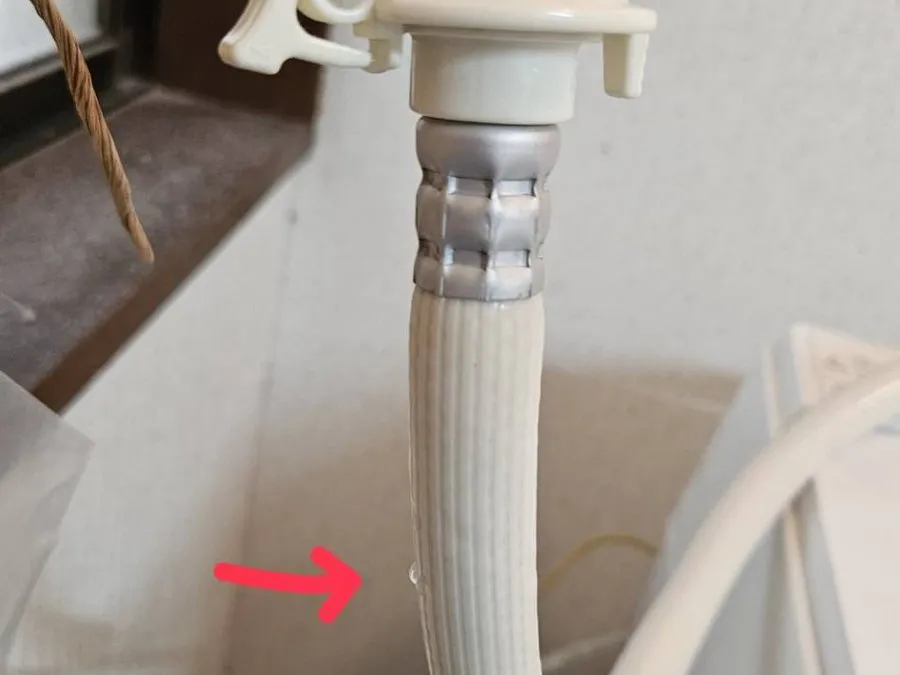 給水ホースを伝って水滴が落ちている。赤い矢印の先が水滴